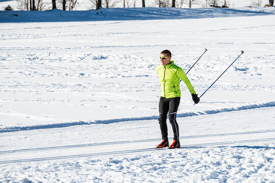 Middle aged man cross country skiing, on the ski trail surrounded by mountains and forest.