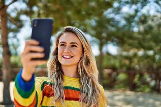 Young blonde woman taking selfie picture at the park