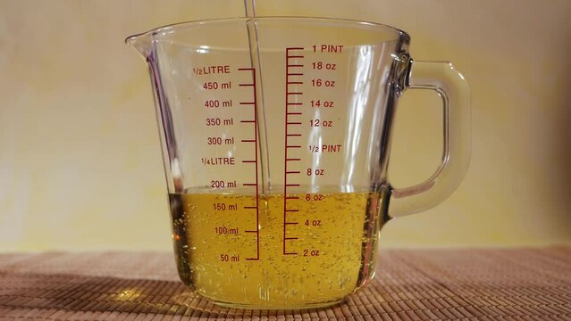 Filling measuring glass jug with vegetable oil close up shot