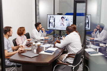 Large group of multi-ethnic medical experts in lab coats listening to their colleague sharing new...