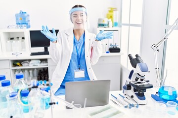 Naklejka premium Young hispanic woman wearing scientist uniform celebrating mad and crazy for success with arms raised and closed eyes screaming excited. winner concept