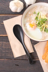 Joke or Congee in a Thai style cup Served on a black wooden table. It's an Asian breakfast. on top view