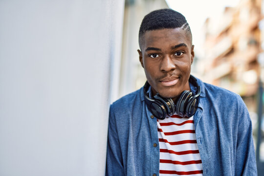Young african american man with serious expression using headphones at the city.