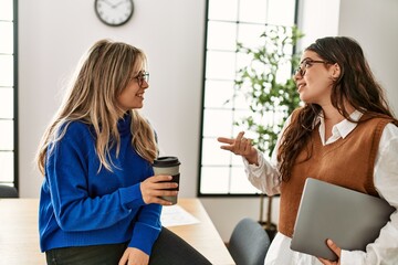 Two business workers woman relaxed drinking coffee and speaking at the office.