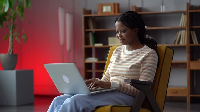 Young african american woman freelance writer or copywriter enjoy working from home type on laptop happy smiling. Inspired female use wireless pc. Girl messaging with friend in social media network