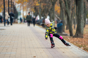 Cute little girl learns to roller skate. A child on roller skates falls