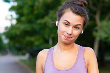 Close-up Portrait of a beautiful young, funny woman. Funny girl with emotions, listens to music in bluetooth wireless headphones.