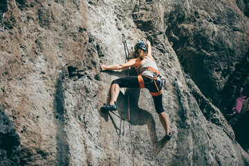 Woman climbing a rock with extreme effort in a vertical rock wall