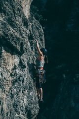 Woman climbing a rock with a lot of climbing gear hanging from her harness