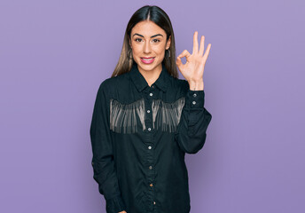 Young hispanic woman wearing casual clothes smiling positive doing ok sign with hand and fingers. successful expression.
