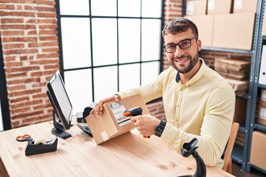 Young hispanic man ecommerce business worker scanning label using barcode reader at office