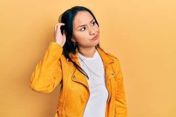 Beautiful hispanic woman with nose piercing wearing yellow leather jacket confuse and wondering...