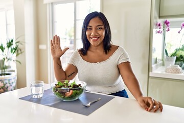 Obraz na płótnie Canvas Young hispanic woman eating healthy salad at home showing and pointing up with fingers number five while smiling confident and happy.