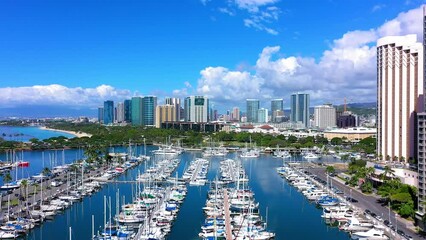 Flying over the marina in Waikiki Hawaii towards the city of Honolulu. Lots of beautiful boats from the aerial drone view.