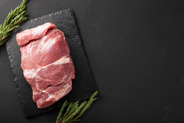  A piece of fresh pork meat on a black background, raw meat on a black board top view copy space...