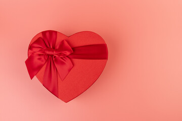 Red box in shape of heart. Gift box for Valentine's Day. Isolated on pink background.