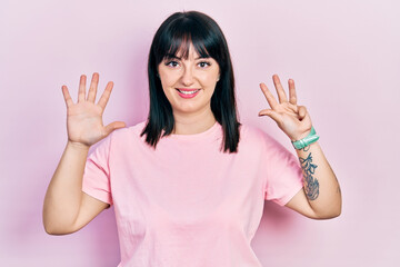 Young hispanic woman wearing casual clothes showing and pointing up with fingers number nine while...