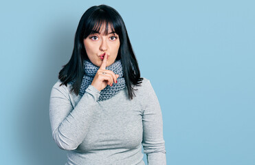 Young hispanic plus size woman wearing winter scarf asking to be quiet with finger on lips. silence and secret concept.