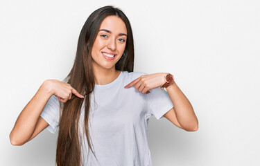 Young hispanic girl wearing casual white t shirt looking confident with smile on face, pointing oneself with fingers proud and happy.