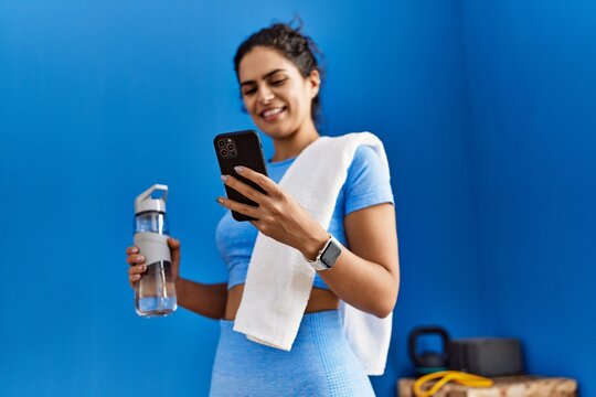 Young latin woman smiling confident using smartphone at sport center