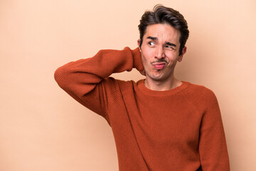 Young caucasian man isolated on beige background touching back of head, thinking and making a...