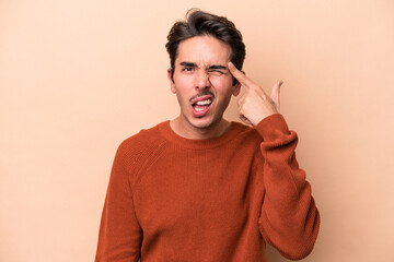 Young caucasian man isolated on beige background showing a disappointment gesture with forefinger.