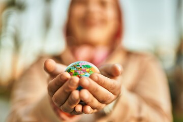 Hands of hispanic woman holding small world ball standing at the city.