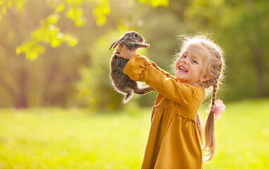 The girl is holding a little rabbit in her arms and laughing