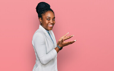Young african american woman wearing business clothes pointing aside with hands open palms showing...