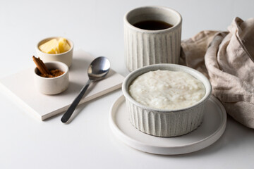 Scandinavian rice porridge on grey ceramic  bowl served with butter and cinnamon. Typical breakfast in many countries.
