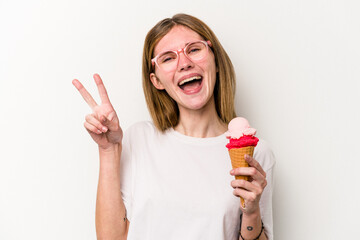 Young English woman holding an ice cream isolated on white background joyful and carefree showing a peace symbol with fingers.