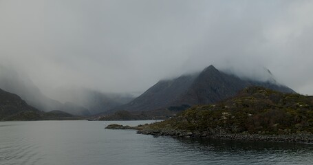 A landscape view of a ferry at sea, with the harbour in the distance, on the Lofoten islands.  