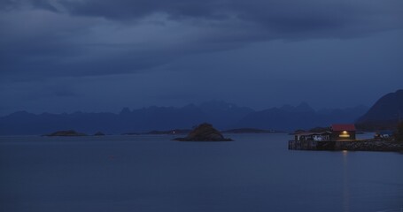 Lofoten islands at blue hour with mountain peaks in the distance and the sea water rippling.