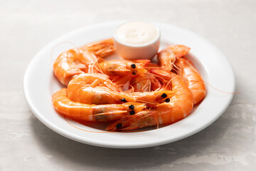 Boiled fresh shrimps with sauce in small bowl on white plate on blue
