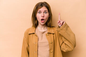 Young English woman isolated on beige background pointing upside with opened mouth.