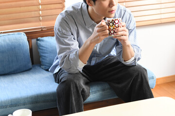 室内で飲み物を飲むリラックス中の若いアジア人男性