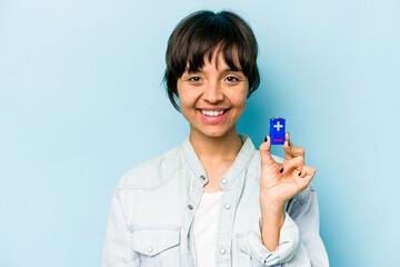 Young hispanic woman holding a batterie isolated on blue background happy, smiling and cheerful.