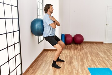 Middle age caucasian man training using fit ball at sport center