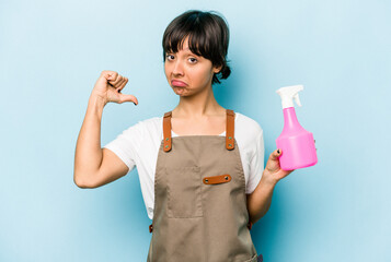 Young hispanic gardener woman holding a hand sprayer isolated on blue background feels proud and self confident, example to follow.