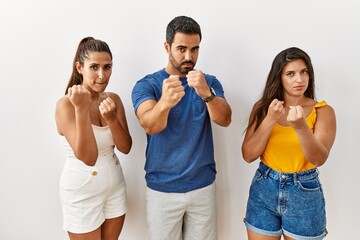 Group of young hispanic people standing over isolated background ready to fight with fist defense gesture, angry and upset face, afraid of problem