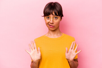 Young hispanic woman isolated on pink background rejecting someone showing a gesture of disgust.