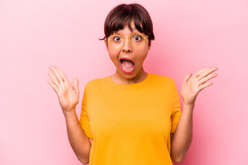 Young hispanic woman isolated on pink background celebrating a victory or success, he is surprised and shocked.