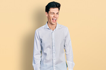 Young hispanic business man wearing business clothes winking looking at the camera with sexy expression, cheerful and happy face.