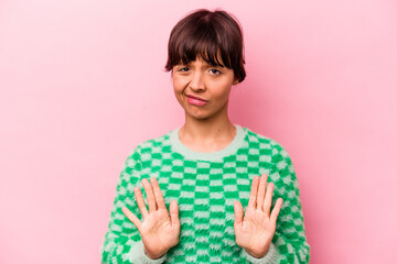 Young hispanic woman isolated on pink background rejecting someone showing a gesture of disgust.