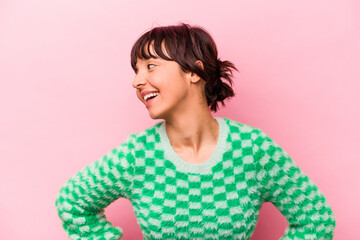 Young hispanic woman isolated on pink background laughs happily and has fun keeping hands on stomach.