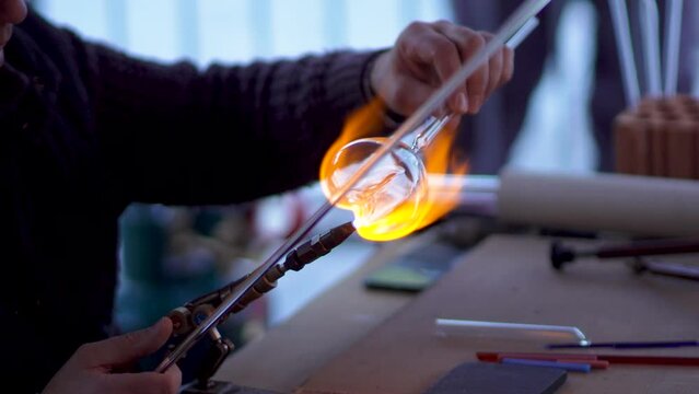 Experienced glass blower working with flame on a handmade art piece of glass