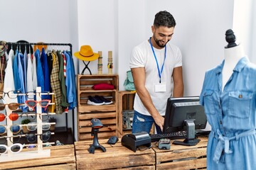Young arab man shopkeeper smiling confident working at clothing store