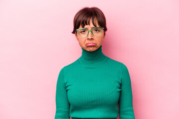 Young hispanic woman isolated on pink background sad, serious face, feeling miserable and displeased.