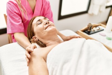 Obraz na płótnie Canvas Middle age caucasian woman having shoulders massage at beauty center