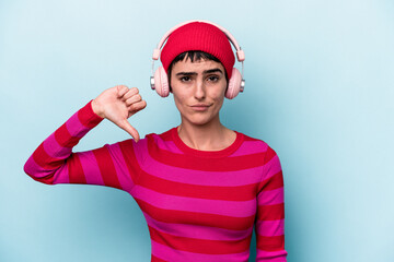 Young caucasian woman listening to music isolated on background showing a dislike gesture, thumbs down. Disagreement concept.